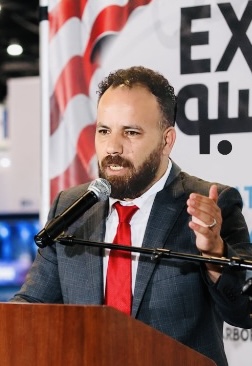 Karim Ayyoub speaking at a podium